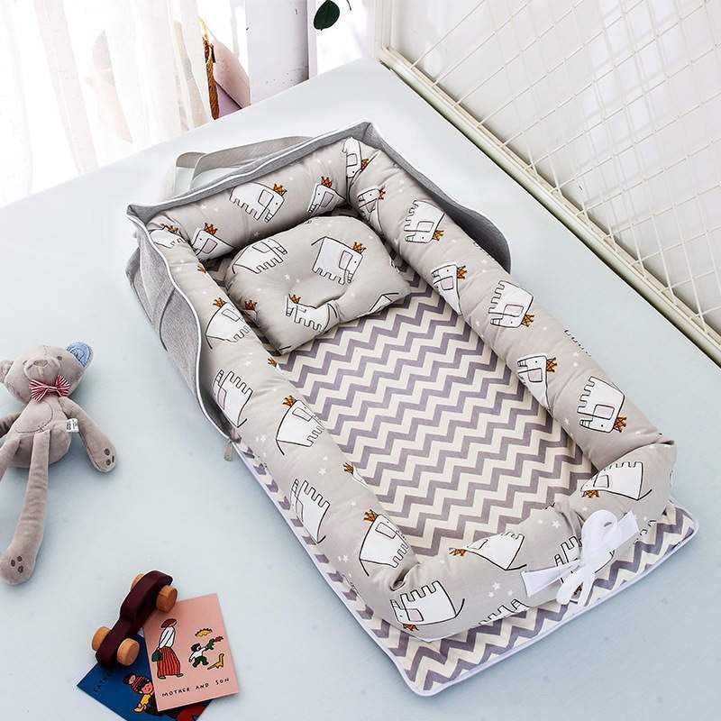 “Portable newborn baby nest and pillow — folds into travel bag with side pockets”